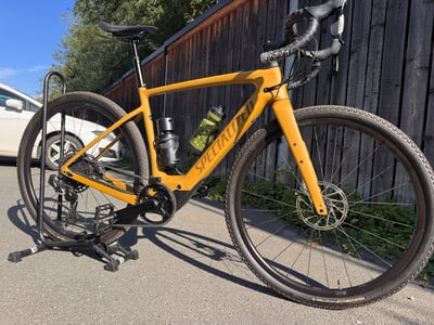 Ein gelbes Specialized Gravelbike auf einem Ständer vor einem Holzzaun. Ein gelbes Specialized Gravelbike auf einem Ständer vor einem Holzzaun.