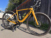 Ein gelbes Specialized Gravelbike auf einem Ständer vor einem Holzzaun.