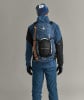 Ein Mann in blauer Kleidung mit Rucksack und Eispickel auf dem Rücken.