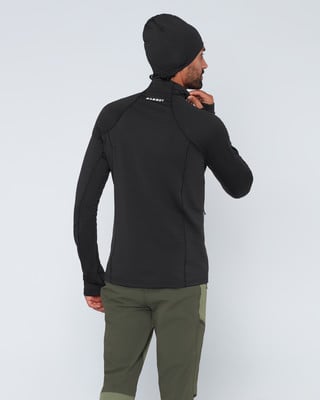 Ein Mann in einem schwarzen Oberteil und grüner Hose blickt über die Schulter. Ein Mann in einem schwarzen Oberteil und grüner Hose blickt über die Schulter.