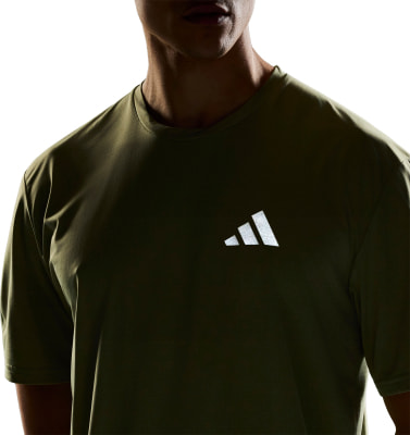 Mann in einem grünen T-Shirt mit Adidas-Logo auf der Brust. Mann in einem grünen T-Shirt mit Adidas-Logo auf der Brust.