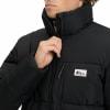 Ein Mann schließt eine schwarze Daunenjacke mit McKinley-Logo auf der Brust.
