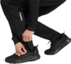 Schwarze Sporthose mit weißem Terrex-Schriftzug und schwarzen Schuhen.