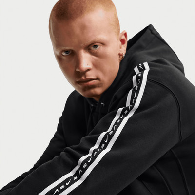 Mann in schwarzem Hoodie mit Nike-Logo auf dem Ärmel. Mann in schwarzem Hoodie mit Nike-Logo auf dem Ärmel.