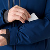 Ein Mann legt eine Karte in eine Ärmeltasche einer dunkelblauen Jacke.