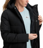 Eine Frau in einer schwarzen Daunenjacke mit Kapuze und einem hellblauen T-Shirt mit Logo.
