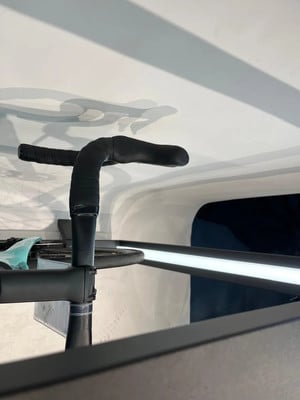 Schwarzer Fahrradlenker mit umwickeltem Lenkerband und Schatten an der weißen Wand.