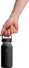 Eine Hand hält eine schwarze Hydro Flask Flasche am Griff vor weißem Hintergrund.