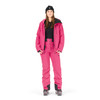 Eine Frau in einer rosa Skijacke, Hose und schwarzer Mütze posiert vor weißem Hintergrund.