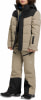 Junge in beiger Daunenjacke und Skihose mit schwarzen Akzenten.