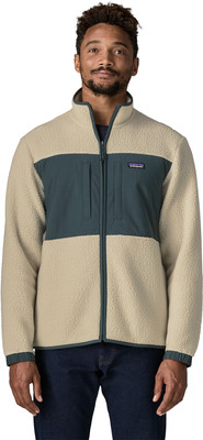 Ein Mann in einer beige Fleecejacke mit dunkelgrünem Einsatz und Logo. Ein Mann in einer beige Fleecejacke mit dunkelgrünem Einsatz und Logo.