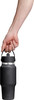 Eine Hand hält eine dunkle Hydro Flask Flasche mit Henkel auf weißem Hintergrund.