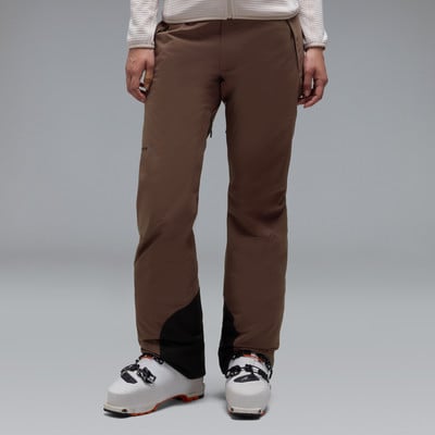 Braune Skihose mit schwarzen Einsätzen und weißen Skischuhen. Braune Skihose mit schwarzen Einsätzen und weißen Skischuhen.