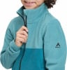 Ein Mädchen schließt eine türkisfarbene Fleecejacke mit einem dunkleren unteren Teil.