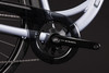 Detail eines Kettenblatts und einer Kette an einem silbernen Fahrrad mit dunklem Schutz.