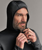 Ein Mann schließt eine schwarze Kapuzenjacke mit einem Logo auf der Brust.