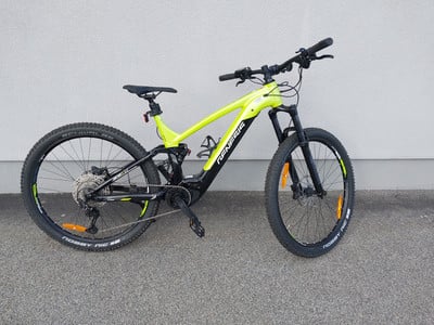 Grünes Mountain-Elektrofahrrad mit Federung, das an einer Wand geparkt ist.
