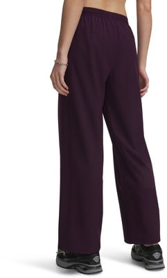 Eine Frau trägt dunkelviolette weite Hosen und schwarze Turnschuhe.