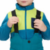 Ein Kind trägt eine blau-grüne Fleecejacke und eine blaue Latzhose.