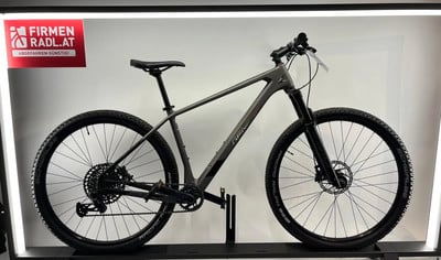 Ein graues Mountainbike mit schwarzen Rädern auf einem Ständer. Ein graues Mountainbike mit schwarzen Rädern auf einem Ständer.
