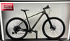 Ein graues Mountainbike mit schwarzen Rädern auf einem Ständer.