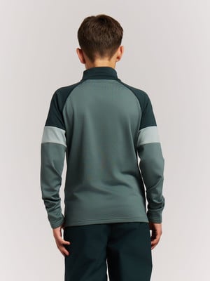 Rückansicht eines Jungen in einem dunkelgrünen Pullover und dunkler Hose.