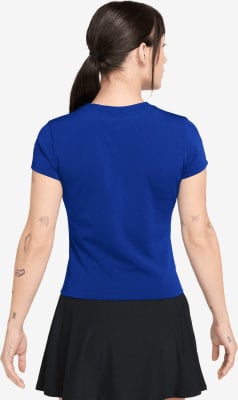 Rückansicht einer Frau in blauem Oberteil und schwarzem Rock mit Tätowierungen.