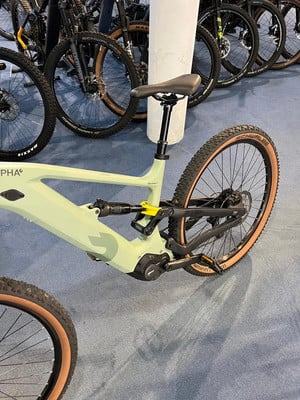 Ein grünes E-Bike mit Federung und braunen Reifen auf blauem Teppich. Ein grünes E-Bike mit Federung und braunen Reifen auf blauem Teppich.