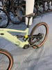 Ein grünes E-Bike mit Federung und braunen Reifen auf blauem Teppich.