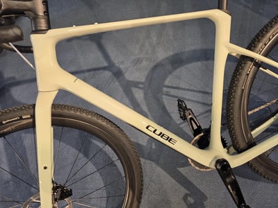 Detail eines hellgrünen Cube Gravelbike-Rahmens mit Rädern und Pedalen. Detail eines hellgrünen Cube Gravelbike-Rahmens mit Rädern und Pedalen.