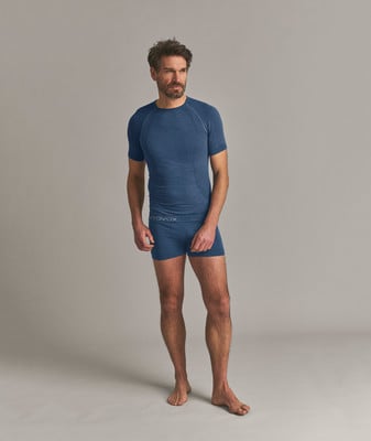 Ein Mann in einem blauen T-Shirt und Unterwäsche steht vor einem grauen Hintergrund. Ein Mann in einem blauen T-Shirt und Unterwäsche steht vor einem grauen Hintergrund.