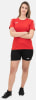 Eine Frau in einem roten T-Shirt und schwarzen Shorts mit verschränkten Armen.