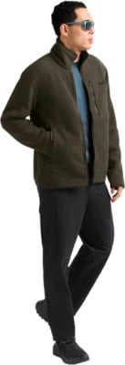 Ein Mann in einer dunkelgrünen Fleecejacke und schwarzer Hose mit blauer Sonnenbrille. Ein Mann in einer dunkelgrünen Fleecejacke und schwarzer Hose mit blauer Sonnenbrille.