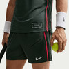 Ein Tennisspieler in dunkler Kleidung hält einen Tennisball und einen Schläger.