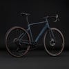 Elegantes dunkelblaues Gravelbike mit braunen Reifen auf schwarzem Hintergrund.