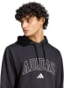 Ein Mann in einem schwarzen Kapuzenpullover mit Adidas-Logo auf der Brust.
