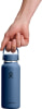 Eine Hand hält eine blaue Hydro Flask Flasche am Griff.