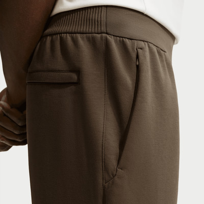 Detail einer Hose mit Tasche und Reißverschluss, braune Farbe.