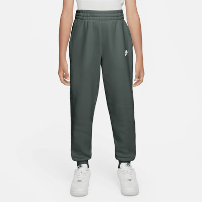 Mädchen in dunkelgrüner Nike Jogginghose mit weißem Logo und Turnschuhen. Mädchen in dunkelgrüner Nike Jogginghose mit weißem Logo und Turnschuhen.