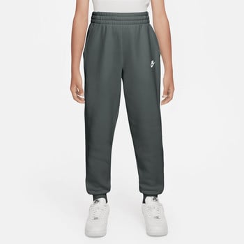 Mädchen in dunkelgrüner Nike Jogginghose mit weißem Logo und Turnschuhen.