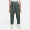 Mädchen in dunkelgrüner Nike Jogginghose mit weißem Logo und Turnschuhen.