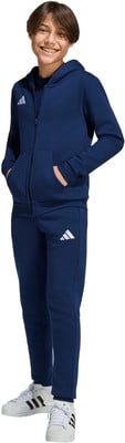 Junge im dunkelblauen Adidas-Anzug mit weißem Logo und Turnschuhen. Junge im dunkelblauen Adidas-Anzug mit weißem Logo und Turnschuhen.