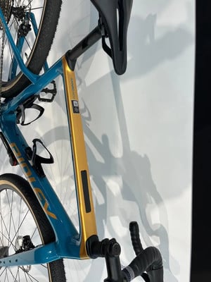 Goldener und blauer Fahrradrahmen mit schwarzem Sattel und Lenker.