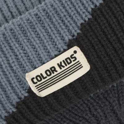 Detail einer gestrickten Mütze mit dem Logo COLOR KIDS in blau-grauen und schwarzen Streifen. Detail einer gestrickten Mütze mit dem Logo COLOR KIDS in blau-grauen und schwarzen Streifen.