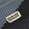 Detail einer gestrickten Mütze mit dem Logo COLOR KIDS in blau-grauen und schwarzen Streifen.