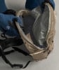 Eine Person zieht einen blauen Handschuh an und öffnet einen beigen Rucksack.