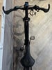 Ein schwarzes E-Bike mit Display und ergonomischem Lenker auf Holzboden.