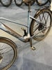 Ein blaues E-Bike mit Gepäckträger und Schutzblechen auf grauem Teppich.