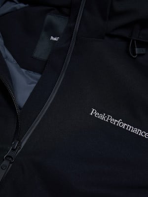 Detail einer schwarzen Jacke mit Peak Performance Logo und Reißverschluss.