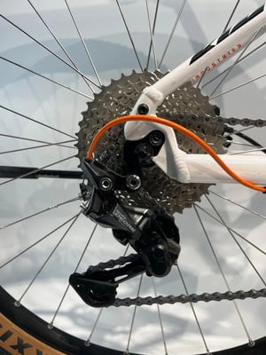 Shimano Deore Schaltwerk an einem weißen Fahrrad mit orangefarbenem Schaltzug. Shimano Deore Schaltwerk an einem weißen Fahrrad mit orangefarbenem Schaltzug.